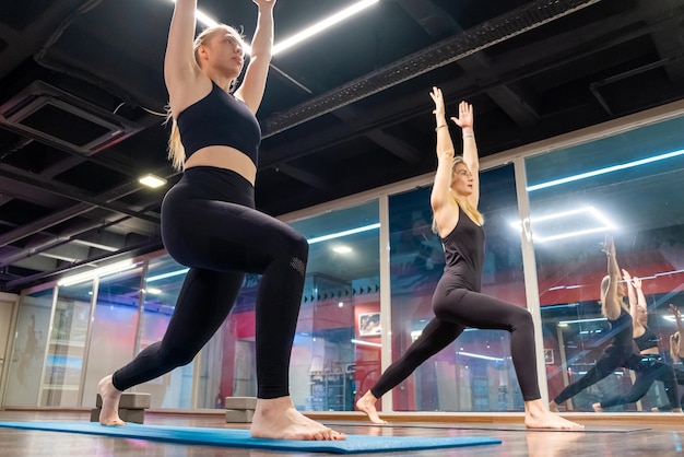 Clase de grupo de estudiantes de profesor de yoga practicando movimientos de enseñanza de yoga que se extienden en pose de estudioyoga