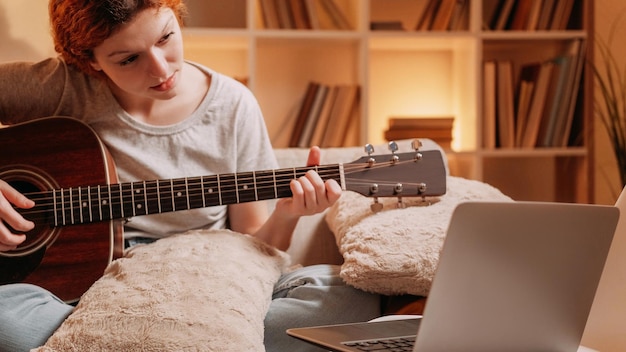 Clase de música en línea curso acústico pasatiempo creativo inspirado músico mujer tocando la guitarra aprendizaje