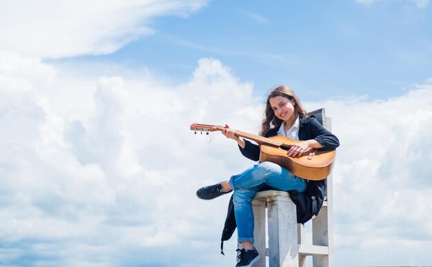 Clases de la escuela de música pequeño guitarrista en el fondo del cielo estilo de música country instrumento musical de cuerda tocar en guitarra acústica niña pequeña tocar la guitarra le encanta el espacio de copia de música