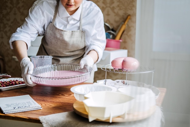 Foto clases y talleres en línea sobre decoración y horneado de pasteles confitería femenina panadera hace pasteles personalizados en forma de corazón rosa en la cocina panadería