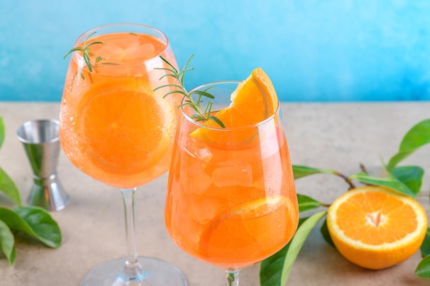 Clásico aperitivo italiano aperol spritz cóctel en dos vasos con hielo naranja sobre fondo azul en el podio de mármol