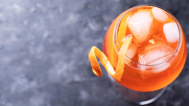 Clásico aperitivo italiano aperol spritz cóctel en vaso con rodaja de naranja en la pared oscura, vista superior