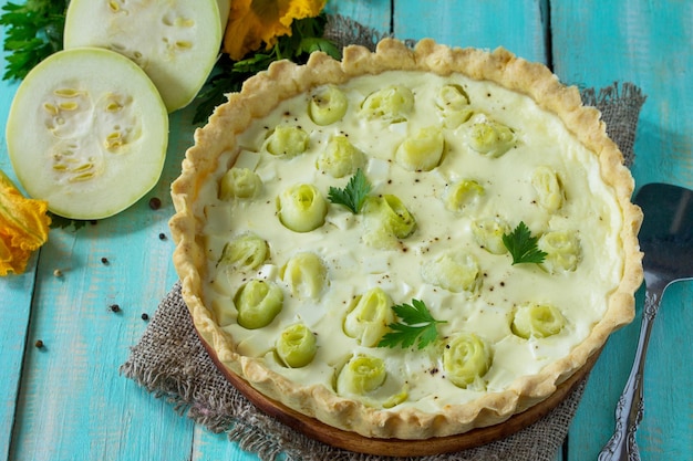 Un clásico pastel de quiche Lorraine con queso feta con huevo de calabacín y queso sobre una mesa de madera de cocina