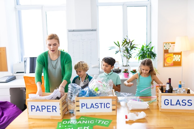 Clasificando la basura juntos. Tres alumnos y su profesor de ecología clasificando basura juntos en la lección