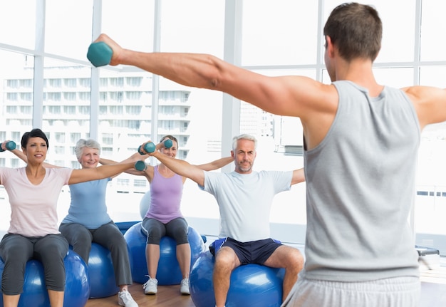 Classe de aptidão com halteres sentados em bolas de exercício