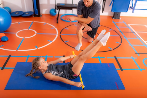 Foto classe de atividade física exercício dos músculos abdominais para crianças com uma barra