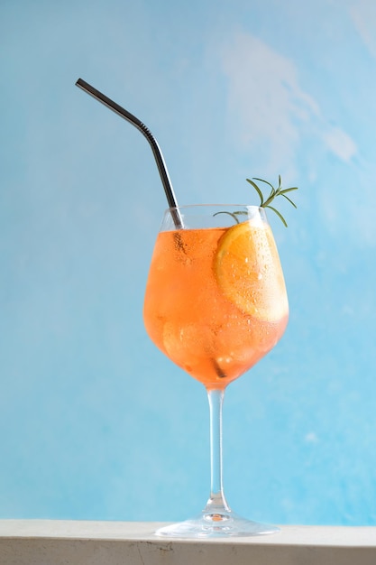 Clássico aperitivo italiano aperol spritz coquetel em vidro com gelo e fatia de laranja em azul claro