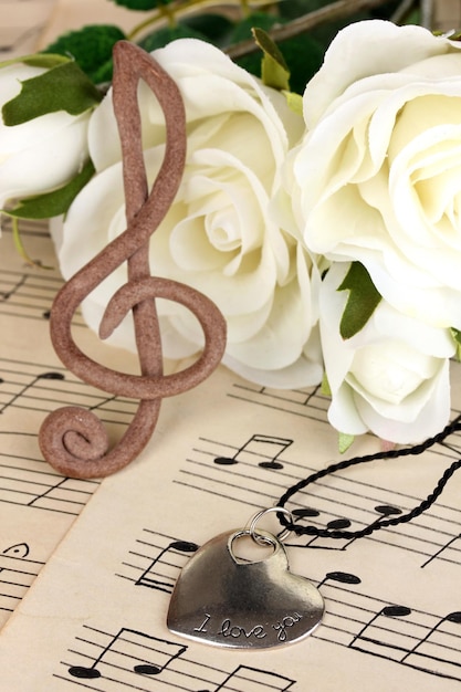 Foto clave de sol, pingente e rosas no fundo musical