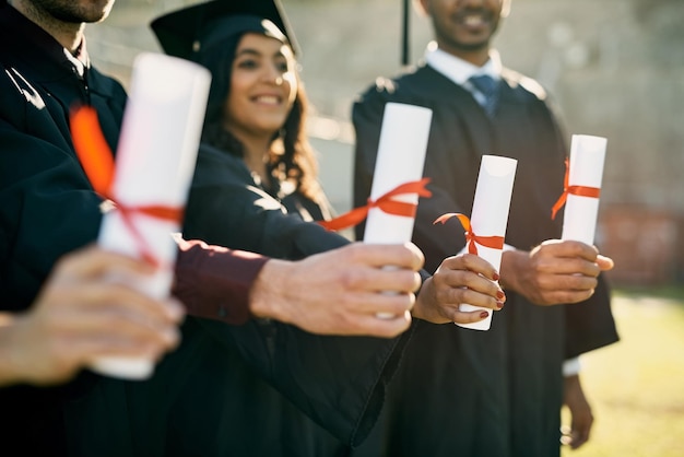 La clave para desbloquear un futuro gratificante Primer plano de un grupo de estudiantes irreconocibles que sostienen sus diplomas el día de la graduación