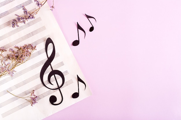 Clave musical de papel e notas de papel em uma folha de música e flores secas Vista superior