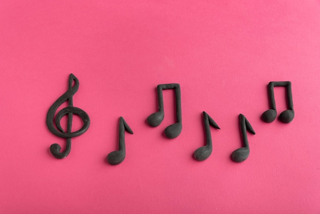 Clave de sol y notas musicales sobre fondo rosa. Símbolo de la música. Llave de G. Llave de violín. Notación musical.