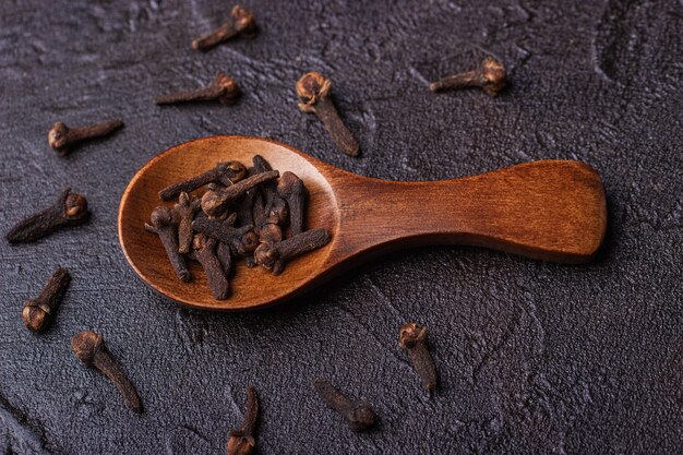 Clavo en una cuchara de madera contra un hormigón oscuro