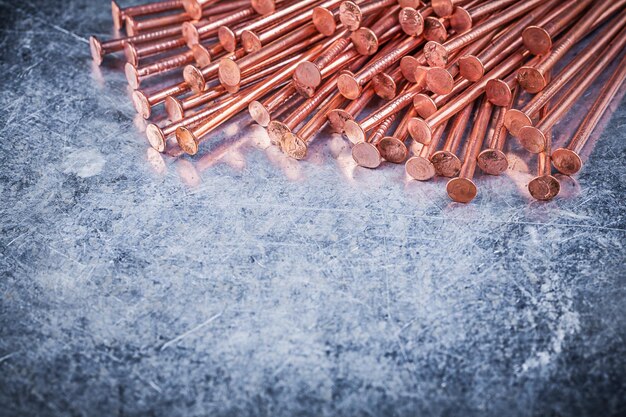 Clavos de construcción de latón sobre fondo metálico