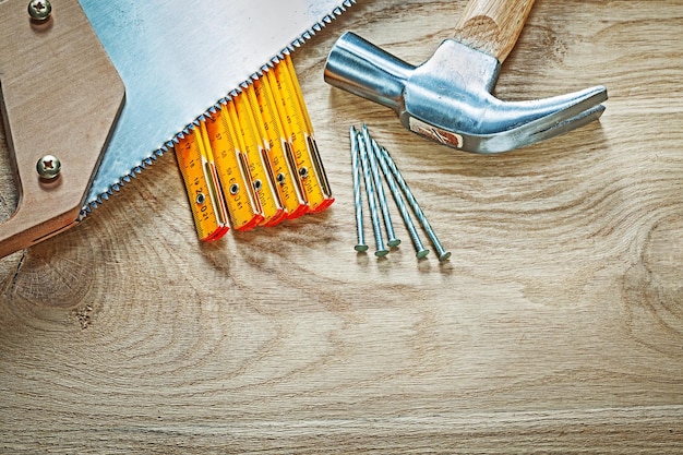 Clavos de sierra de mano de medidor de madera de martillo en concepto de construcción de tablero de madera