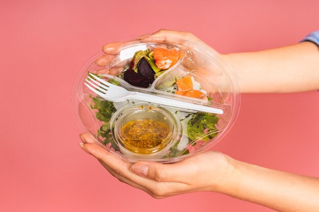 Clean Eating Diätkonzept Asiatische Frau, die vegetarischen Salat oder Schüssel im Take-Away-Container hält Nahaufnahme des Kopierraums Draufsicht isoliert über rosa Hintergrund