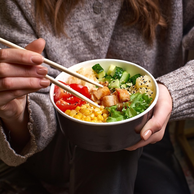 Clean-Eating-Diätkonzept Hühnerschüssel mit Avocado im Papierbehälter zum Herausnehmen in den Händen einer Frau, die eine Mittagspause macht