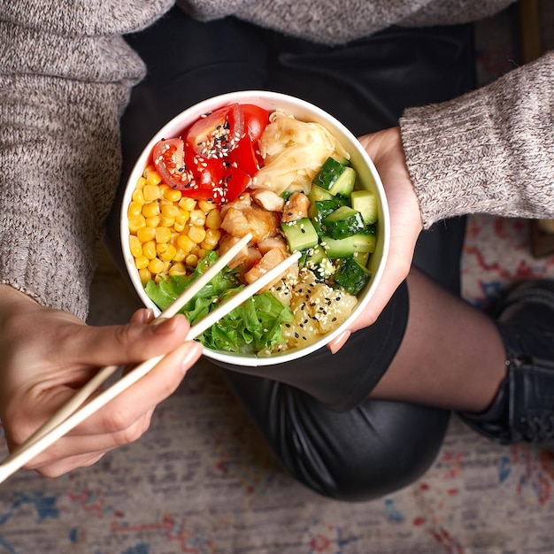 Foto clean-eating-diätkonzept hühnerschüssel mit avocado im papierbehälter zum mitnehmen in den händen einer frau, die eine mittagspause macht nahaufnahme des kopierraums von oben