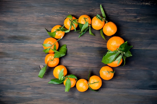 Clementina de tangerinas com folhas em uma mesa de madeira.