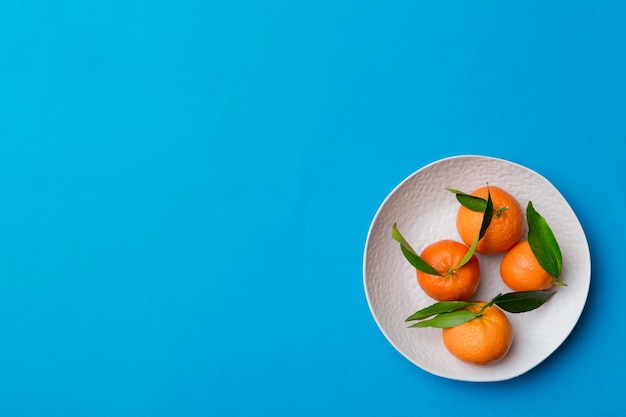 Clementinas frescas cortadas e tangerina inteira sobre prato redondo em fundo colorido Ingredientes de comida e bebida preparando vista superior de tema de alimentação saudável com espaço de cópia