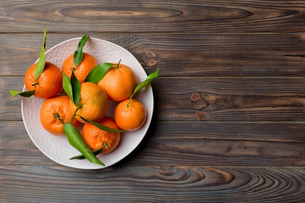 Clementinas frescas cortadas e tangerina inteira sobre prato redondo em fundo colorido Ingredientes de comida e bebida preparando vista superior de tema de alimentação saudável com espaço de cópia