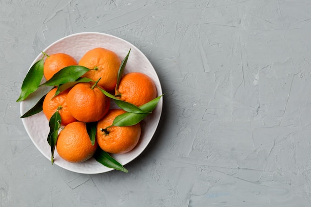 Clementinas frescas cortadas y mandarina entera sobre un plato redondo sobre fondo de color Ingredientes de alimentos y bebidas que preparan la vista superior del tema de alimentación saludable con espacio de copia