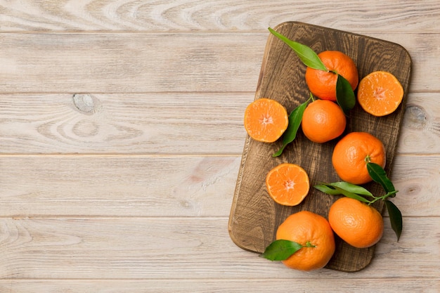 Clementinas frescas cortadas y mandarina entera sobre un plato redondo sobre fondo de color Ingredientes de alimentos y bebidas que preparan la vista superior del tema de alimentación saludable con espacio de copia