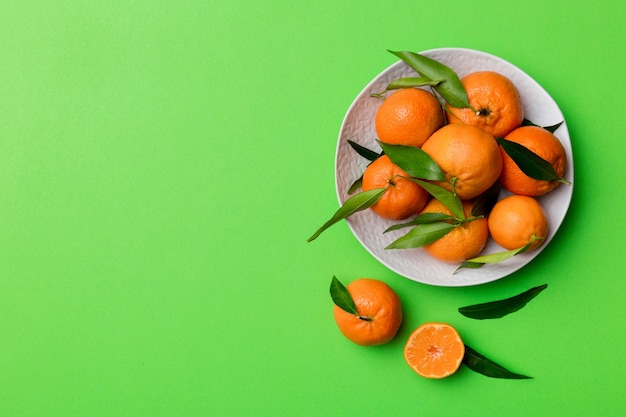 Clementinas frescas cortadas y mandarina entera sobre un plato redondo sobre fondo de color Ingredientes de alimentos y bebidas que preparan la vista superior del tema de alimentación saludable con espacio de copia