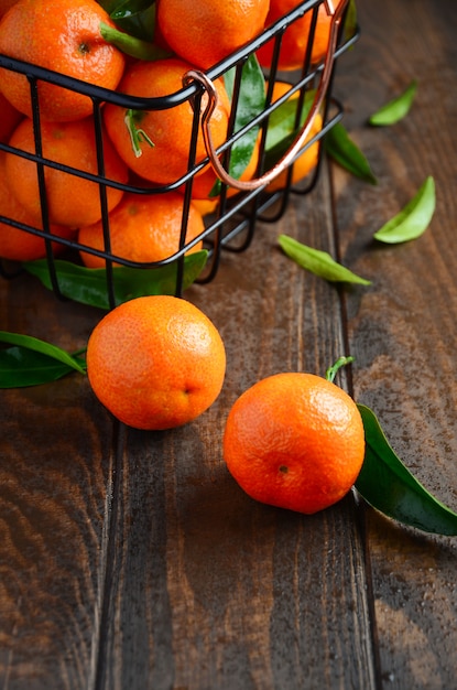 Clementinas frescas de la mandarina con las hojas en fondo de madera oscuro.