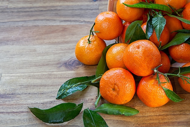 Clementinas con hojas sobre superficie de madera