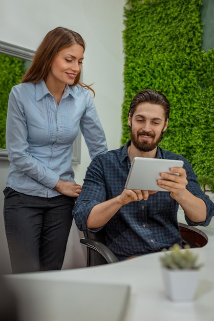 Clevere fortschrittliche junge Ingenieure, die im Büro an einem ökologischen Bauprojekt an einem digitalen Tablet arbeiten und über ein grünes Projekt sprechen.