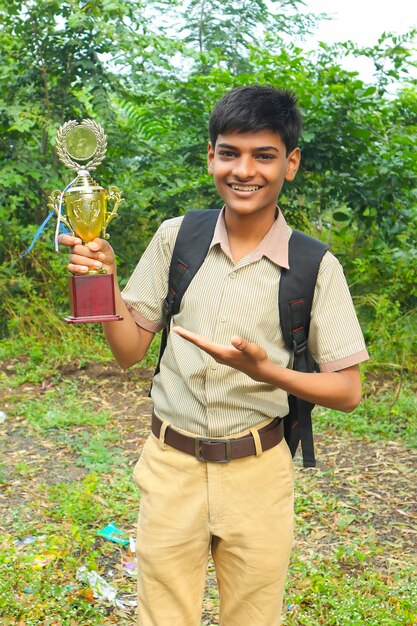 Cleverer Schüler, der seine Trophäe als Sieger im Schulwettbewerb anhebt