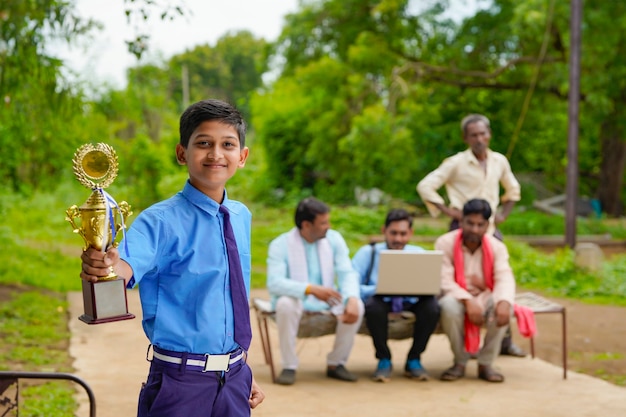 Cleverer Schüler, der seine Trophäe als Sieger im Schulwettbewerb hochhebt.