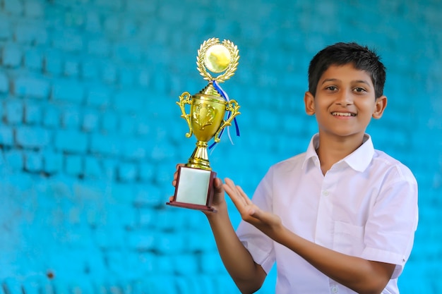 Cleverer Schüler, der seine Trophäe als Sieger im Schulwettbewerb hochhebt.