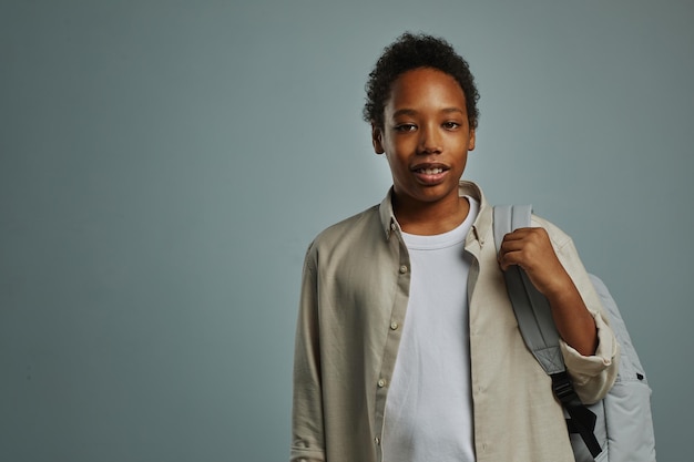 Cleverer Schuljunge mit Rucksack, der vor der Kamera steht, während er während einer Fotosession im Gestüt posiert