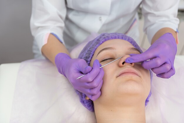 La clienta está recibiendo tratamiento facial con la ayuda de la cosmetología del ojo y la rutina de cuidado de la piel.