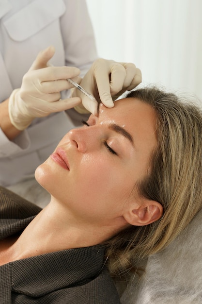 Clienta durante inyecciones de relleno facial en clínica médica estética