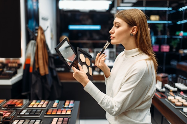 Clienta mira el espejo en la tienda de maquillaje