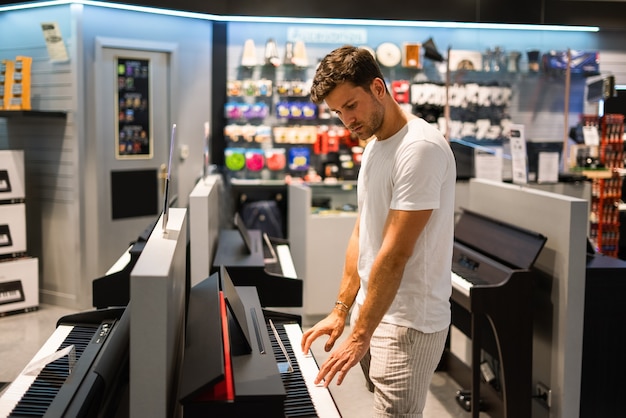 Cliente atento eligiendo piano en la tienda de música