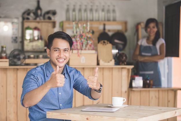 Cliente de café satisfecho mostrando el pulgar hacia arriba