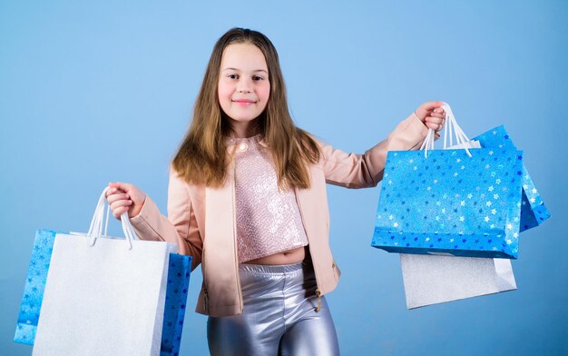 Cliente de chica de moda Niño feliz en la tienda con bolsas Felicidad del día de compras Chica de cumpleaños de compras Boutique de moda Tendencia de moda Tienda de moda Niña con paquetes de racimo Comprar ropa