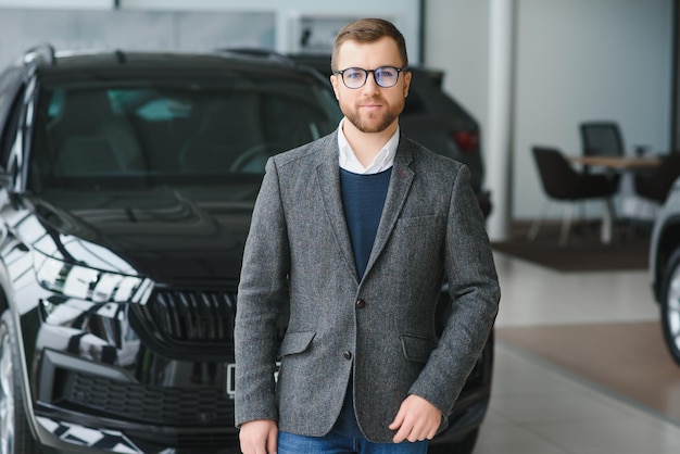 Cliente comprador masculino de terno, escolha o automóvel para ir olhar para o lado, quer comprar automóvel novo no showroom do carro, salão da concessionária, loja do salão do automóvel, conceito de vendas interno