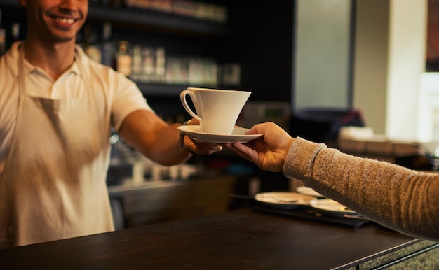 Foto cliente de cafeteria pessoas felizes e mãos de barista com xícara de chá expresso ou matcha para hidratação matinal servidor e garçom da indústria de restaurantes de hospitalidade dando bebida ou líquido ao cliente