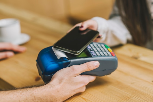 Cliente de colheita pagando com smartphone no café