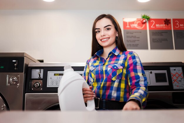 Cliente de lavanderia, segurando uma garrafa de detergente wahsing. Conceito de lavanderia