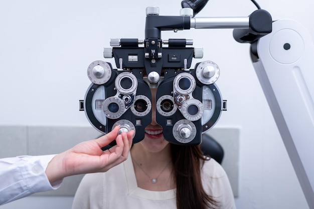 Cliente de loja de óptica feminina fazendo medição de visão com foróptero óptico verifica a distância do olho para
