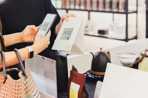 Cliente de mulheres pagando por leitura de código QR no celular na loja