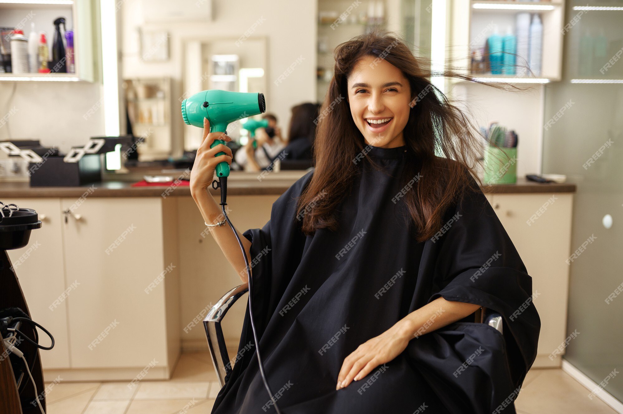 mulher jovem e bonita usando secador de cabelo no salão de