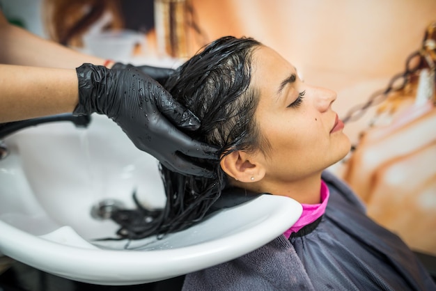 Cliente do sexo feminino lava o cabelo no salão cabeleireiro profissional lava a cabeça do cliente do sexo feminino