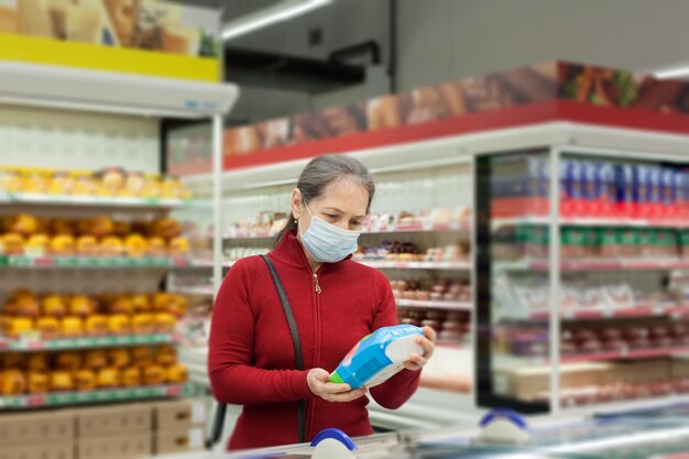 Cliente do sexo feminino sênior com cesta de compras no supermercado usando máscara médica protetoraxDxA