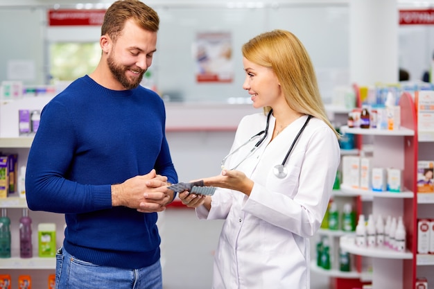 Cliente do sexo masculino conversando discretamente com o farmacêutico na farmácia